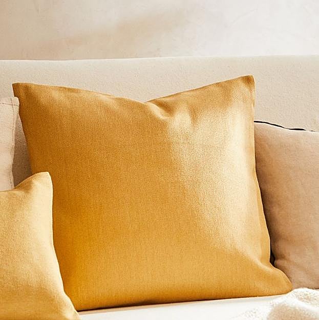 Una funda de cojín en color amarillo mostaza para darle el toque de color a tu salón.