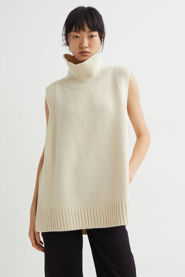 Chaleco sin mangas en punto fino de lana con cachemira, cuello alto y diseño largo y amplio, en crema, de H&M. Puedes comprarlo por 79,99 euros.