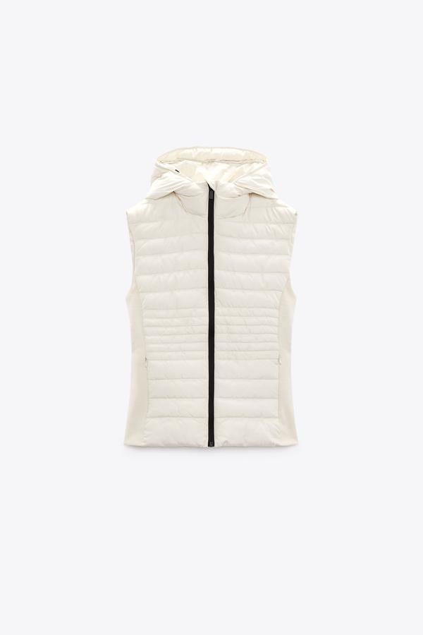 Chaleco de cuello subido con capucha ajustable y cordones elásticos. Puedes conseguirlo en color crudo o negro, dos básicos de armario. Es de Zara. Precio: 29,95 €.