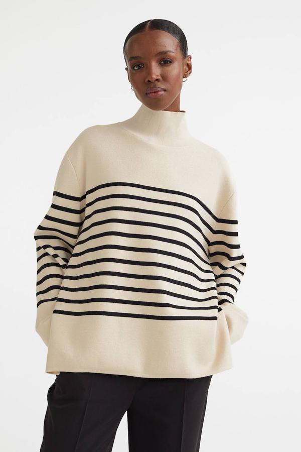 Jersey de punto oversize con silueta relajada, manga larga, aberturas laterales y cuello elevado, en estampado a rayas beige claro y negro, de H&M. Lo encontrarás a 39,99 euros.