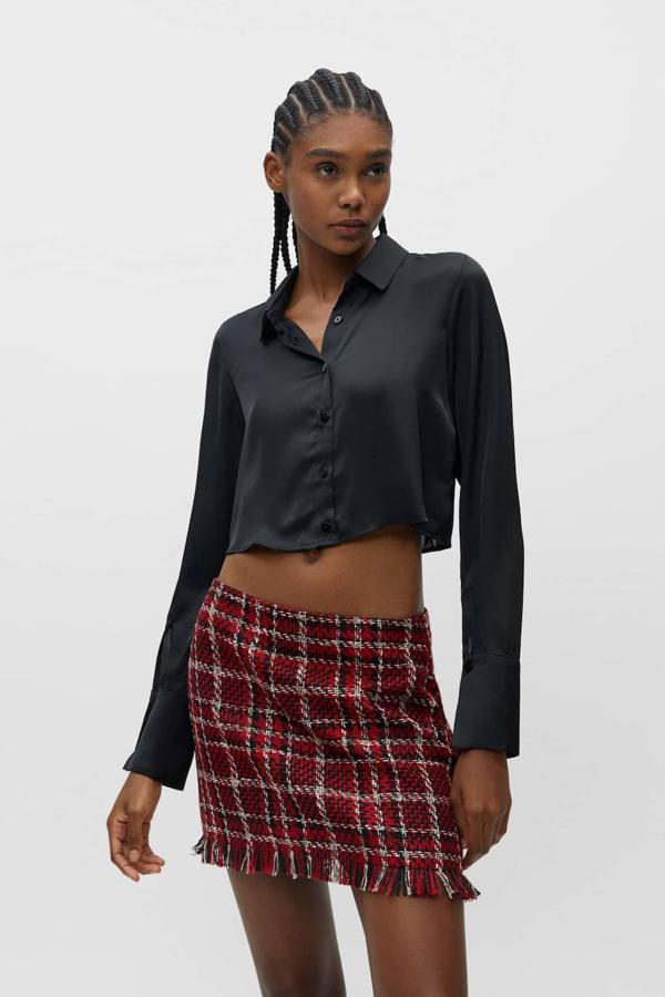 Camisa cropped en tejido fluido satinado con cuello solapa y manga larga acabada en campana, color negro, de Pull&Bear. Está disponible a 19,99 euros.