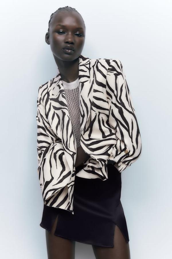 Blazer abierta de cuello solapa y manga por debajo del codo acabada en vuelta con trabilla y botón dorado. Disponible en estampado negro sobre fondo crudo y seis colores: verde, morado, negro, marfil, fucsia y azul. Precio: 39,95 euros.