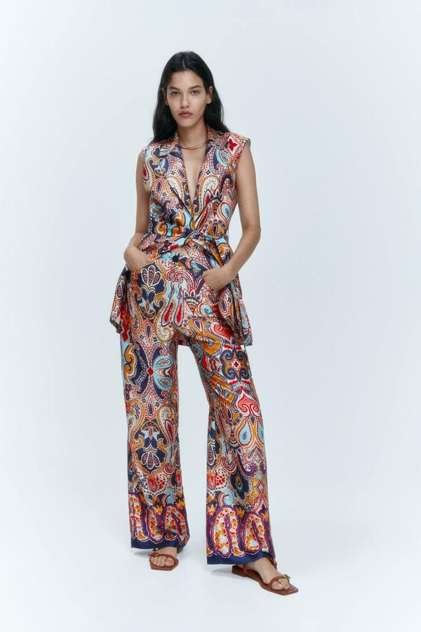 Conjunto en tejido luminoso con estampado paisley multicolor compuesto por chaleco largo con cinturón de lazada y pantalón de tiro alto y pernera recta y ancha, de Zara. Puedes comprar las prendas a 45,95 euros y 29,95 euros, respectivamente.