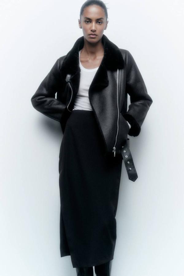 Cazadora doble faz en tejido efecto piel y pelo combinado a tono, con manga larga, cuello solapa, cierre de cremallera cruzado, bolsillos y cinturón ajustable, color negro, de Zara. La encontrarás a 79,95 euros.