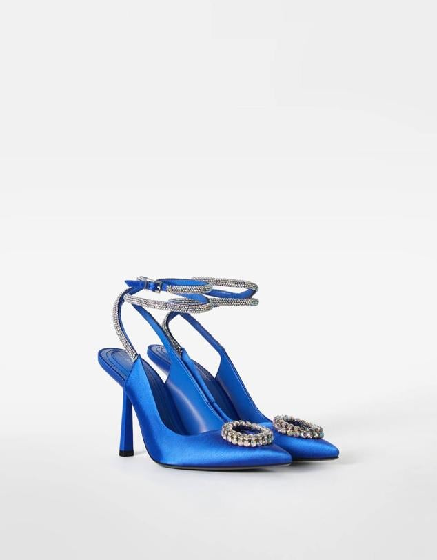 Zapato de tacón destalonado en tejido satinado, terminado en punta, con tiras para amarrar al tobillo y detalle de hebilla y brillos, color azul, de Bershka. Cuesta 49,99 euros. Cómpralo aquí
