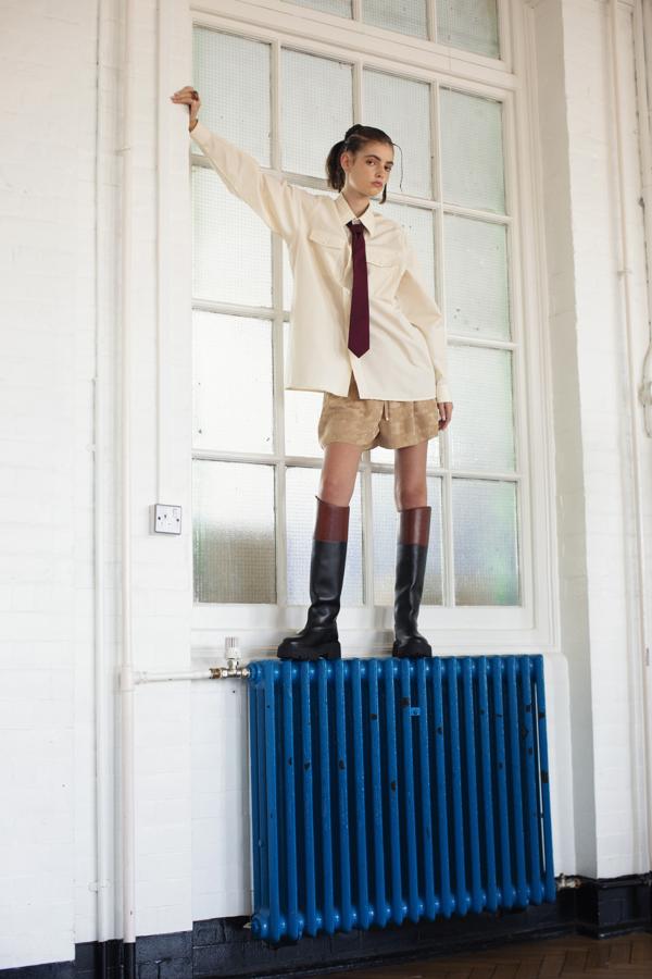 Camisa de Louis Vuitton, corbata de Prada, y shorts y botas de Celine by Hedi Slimane. Los anillos son de Gucci y los pendientes, de Anmaes Beads.