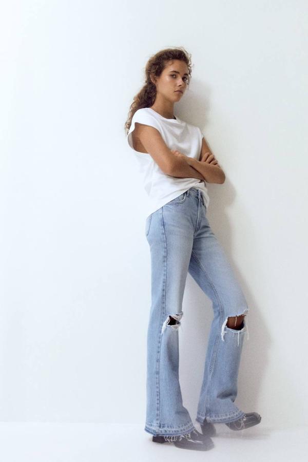 Pantalón vaquero con pernera holgada y ligeramente acampanada, tiro bajo, detalles rotos en las rodillos y bajo sin rematar, color azul claro, de Pull&Bear. Tienen un precio de 29,99 euros.