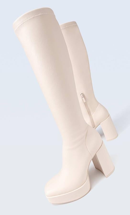 Botas altas con caña ajustada, tacón grueso y plataforma, en color crudo, de Stradivarius. Están disponibles a 55,99 euros.