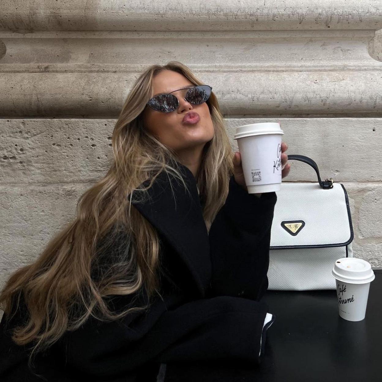 La influencer luce un vestido negro que combina con una chaqueta gruesa del mismo color. 