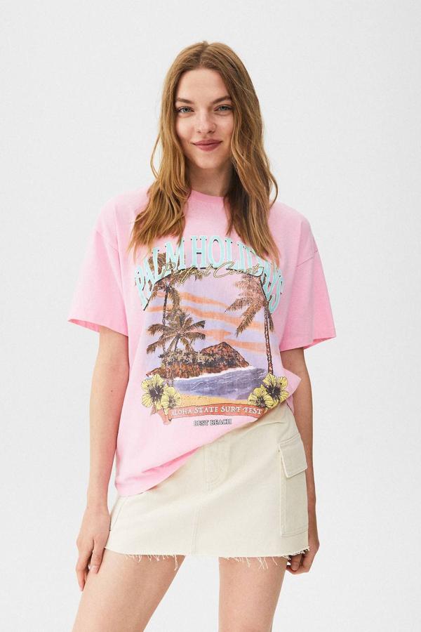 Camiseta de manga corta con cuello redondo, corte holgado y gráfico estampado multicolor, en rosa, de Pull&Bear. Su precio es de 15,99 euros.