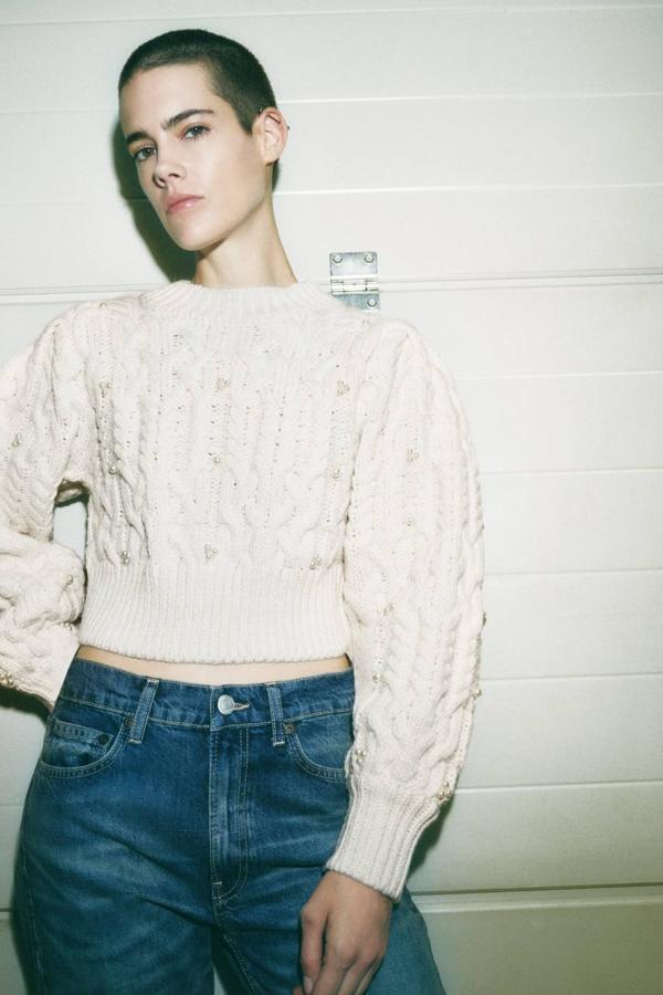 Jersey de punto grueso con diseño de ochos, manga larga abombada, cuello redondo y detalles de perlas, en crudo. Tiene un precio de 35,95 euros.