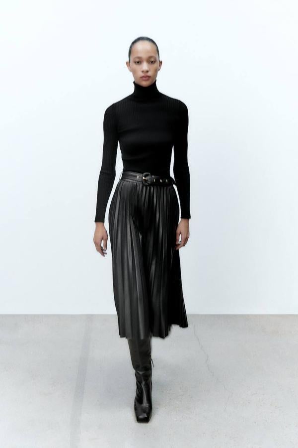 Falda midi plisada en tejido efecto piel con tiro alto, diseño acabado en evasé y cinturón con hebilla combinado, en negro, de Zara. Hazte con ella por 39,95 euros.