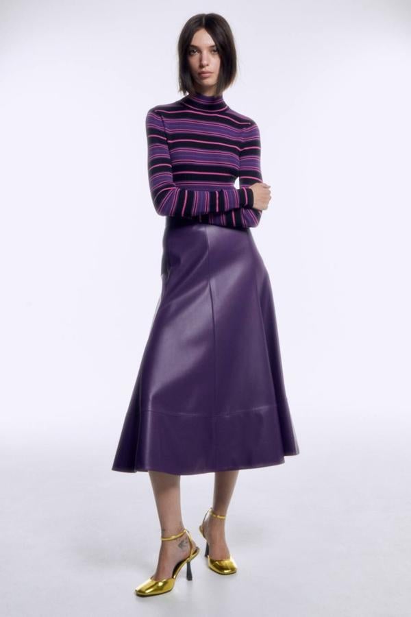 Falda midi en tejido de polipiel con tiro alto y diseño acampanado, en tono morado, de Sfera. Tiene un precio de 39,99 euros.