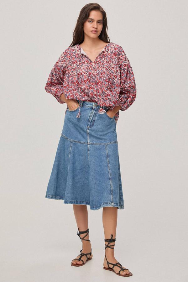 Falda midi vaquera con tiro alto, bolsillos y bajo acabado en evasé, color azul medio, de Pedro del Hierro. Está disponible en Cortefiel a 49 euros.