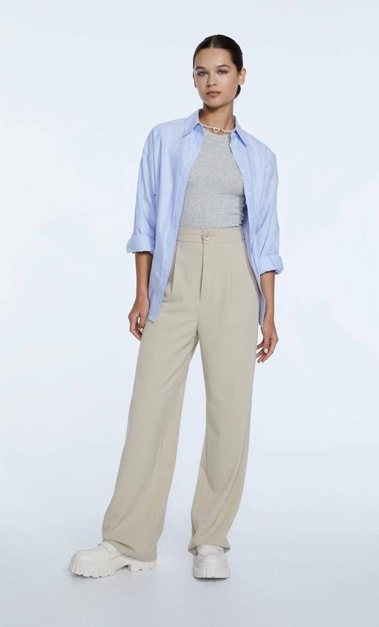 Pantalón largo con perneras anchas y rectas estilo wide leg, detalles de pinzas, bolsillos, tiro alto y cintura elástica, en beige claro, de Stradivarius. Los encontrarás por 22,99 euros.