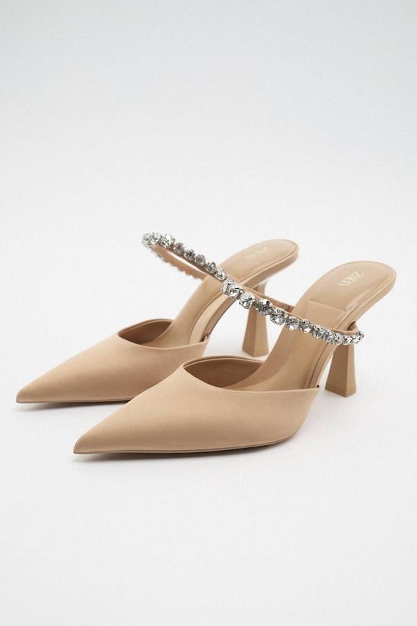 Zapatos mule de tacón piramidal con diseño destalonada, terminados en punta y detalle de tira con brillos, en beige, de Zara. Cuestan 35,95 euros.