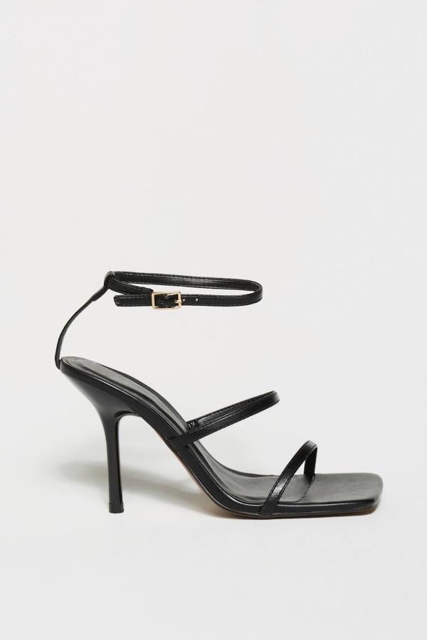 Sandalias de tacón fino con tiras delanteras y pulsera al tobillo, color negro, de Sfera. Su coste es de 35,99 euros.