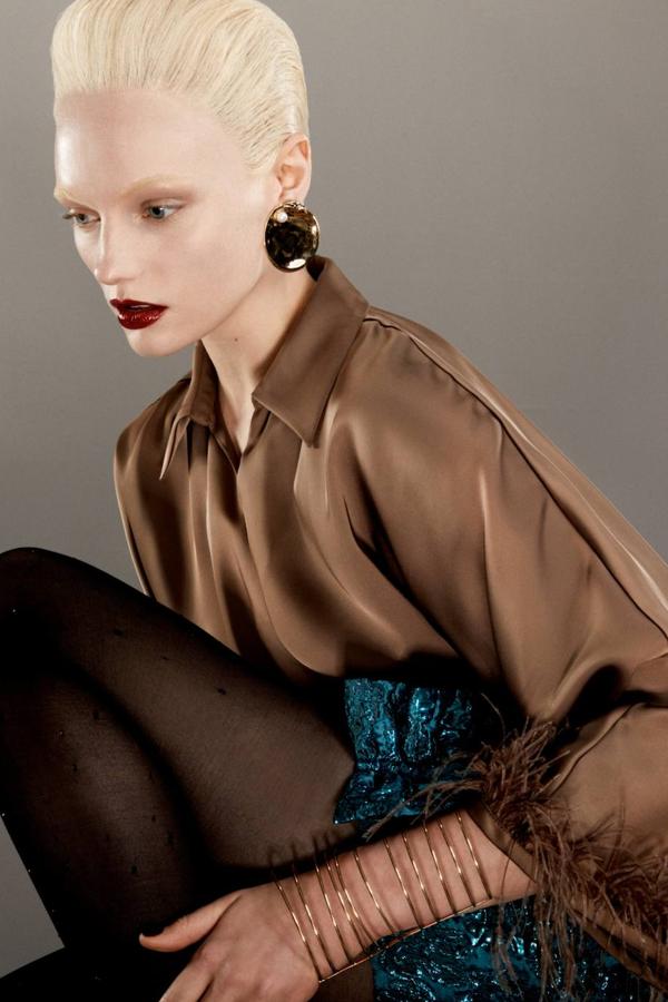 Blusa en tejido satinado con diseño cruzado, corte relajado, cuello solapa y mangas anchas adornadas con plumas, en tono marrón, de Zara. Hazte con ella por 39,95 euros.