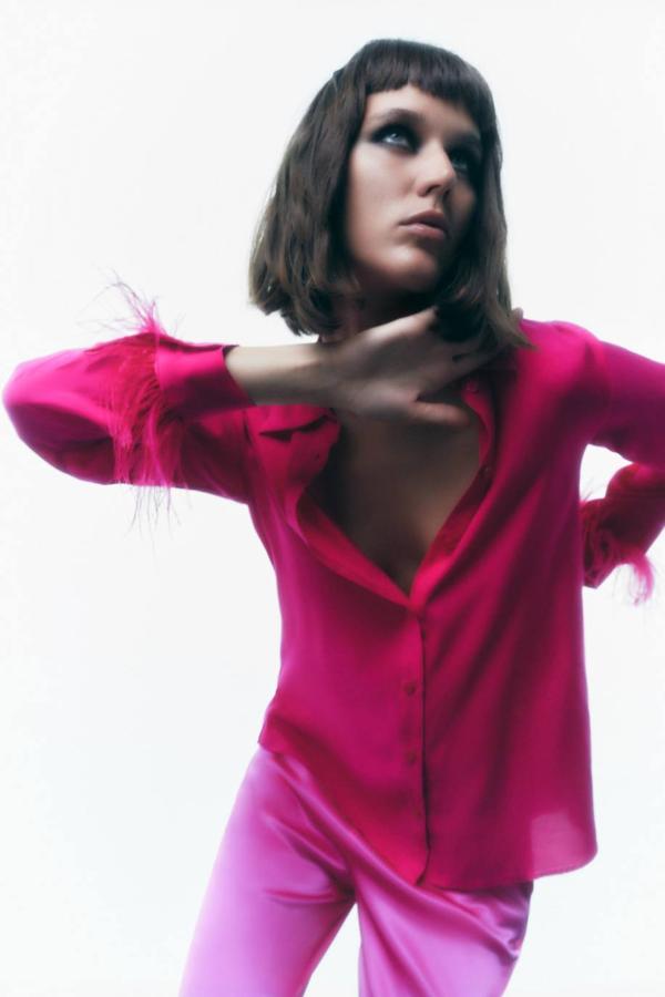 Camisa fluida satinada con cuello solapa, cierre de botones y manga larga con puños de plumas, color fucsia, de Zara. La encontrarás a 35,95 euros.