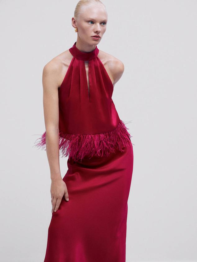 Top en tejido fluido satinado con cuello halter, corte eváse, detalles fruncidos, abertura y bajo acabado en plumas, en rosa frambuesa, de Massimo Dutti. Está disponible por 89,95 euros.