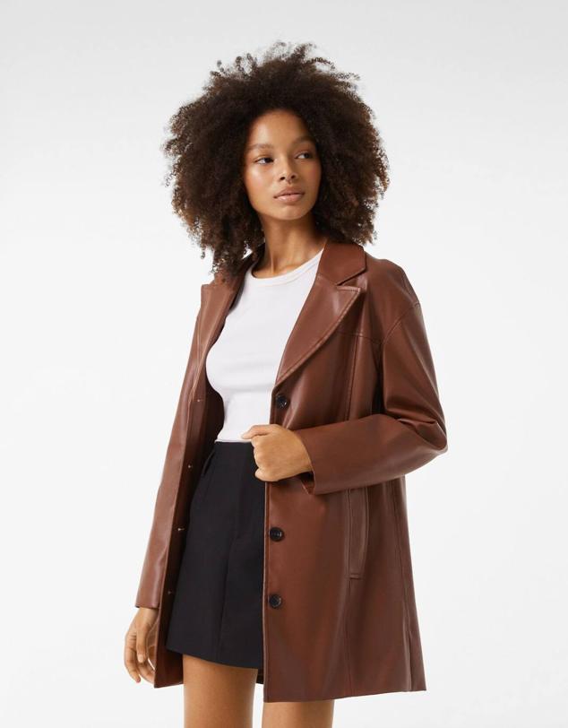 Blazer efecto piel con diseño largo, corte relajado, manga larga, cuello solapa con muesca, bolsillos laterales y cierre de botones, en marrón medio, de Bershka. Consíguela por 39,99 euros.