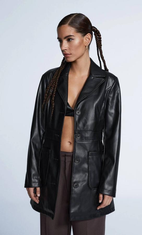 Americana larga en tejido efecto piel con diseño estructurado y entallado, cierre de botones a tono, manga larga, cuello solapa con muesca y bolsillos de plastrón, en negro, de Stradivarius. Está disponible por 45,99 euros.