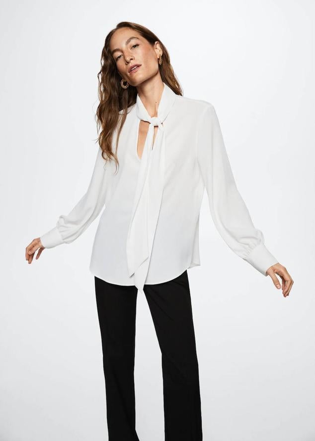 Blusa fluida con manga larga, escote de pico y detalle de lazada al cuello, de Mango. Su precio es de 19,99 euros.