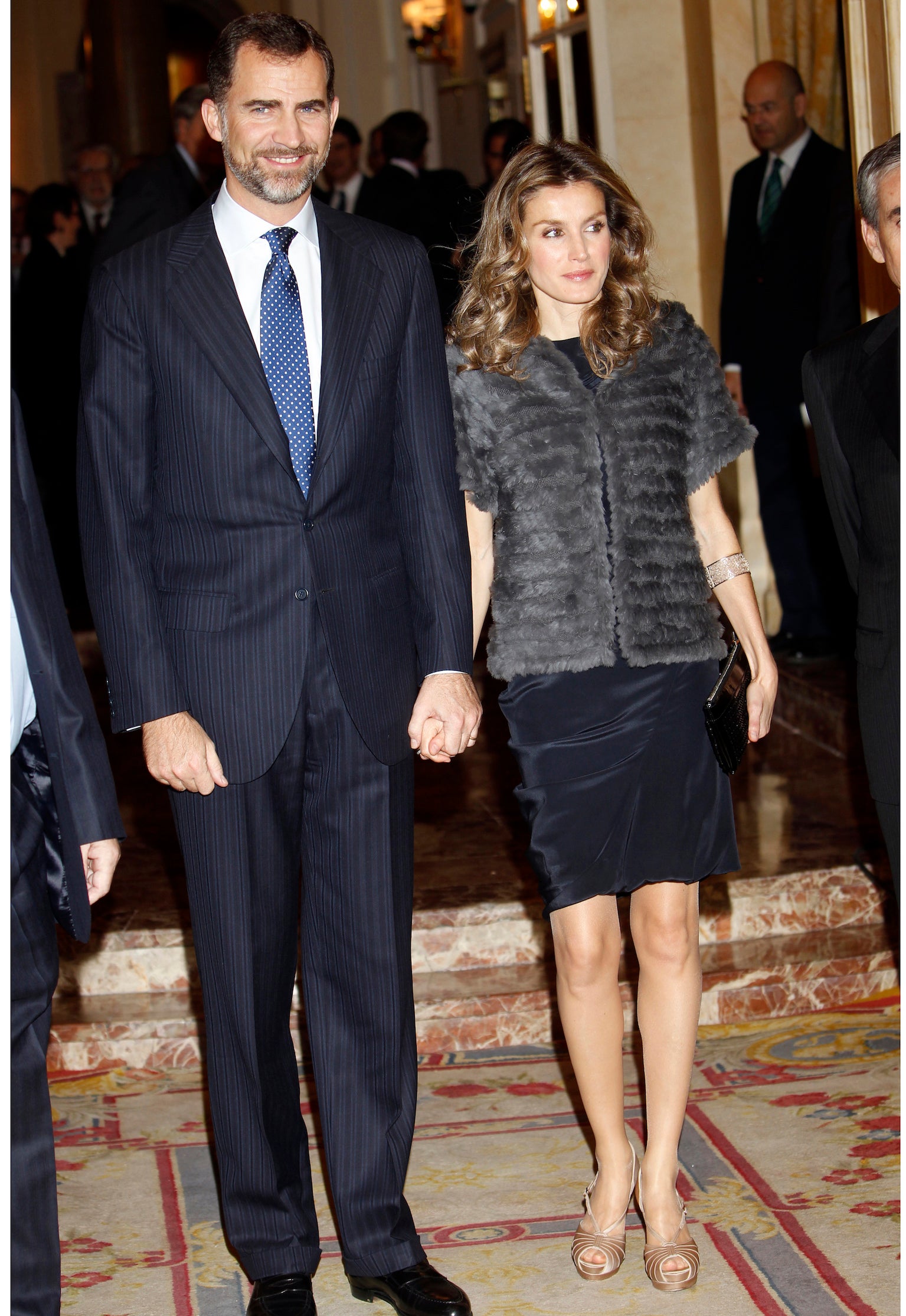 El ‘petit robe noir’ de Hugo Boss que la reina eligió en esta ocasión fue un acierto. Una pena que lo combinara con un inexplicable chaleco de pelo gris con capucha y unos salones dorados. 