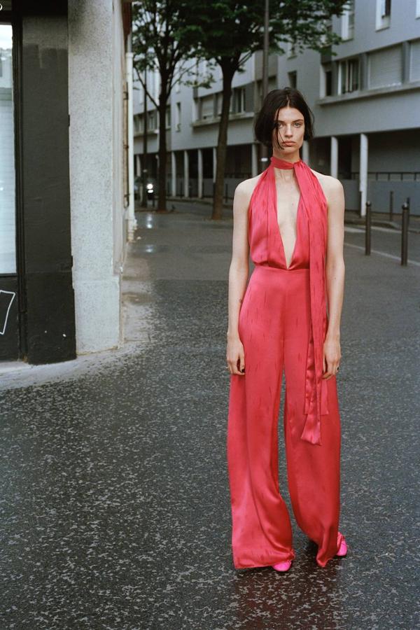 Mono largo en tejido satinado fluido con escote pronunciado, lazada al cuello y maxi perneras, en frambuesa, de Zara. Tiene un precio de 49,95 euros.