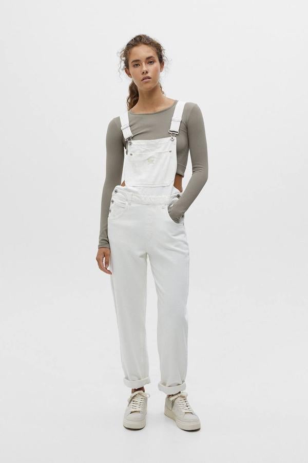 Peto largo en tejido denim con perneras rectas, bolsillos, tirantes ajustables y escote recto, en blanco, de Pull&Bear. Su coste es de 29,99 euros.
