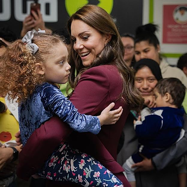 Kate Middleton cumplió con su agenda a pesar de los abucheos, como esta visita a un colegio, donde cogió en brazos a una niña. 