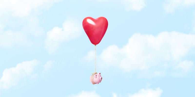 Horizontal conceptual image of a single pink piggy bank tied to a red heart balloon with a rope floating through the clouds, could illustrate concepts like couple and relationship finances, dating costs, moving away from home, or even opposite things like loosing ones savings in a divorce or breakup