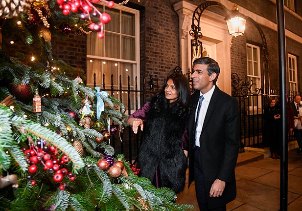 LONDON, ENGLAND - NOVEMBER 30: British Prime Minister Rishi Sunak and his wife Akshata Murty look at a Christmas tree after visiting a food and drinks market promoting British small businesses over the festive season at Downing Street on November 30, 2022 in London, England. In recent years, a festive food and drink market has been created on Downing Street to showcase British vendors of Small Business Saturday. (Photo by Toby Melville - Pool / Getty Images)