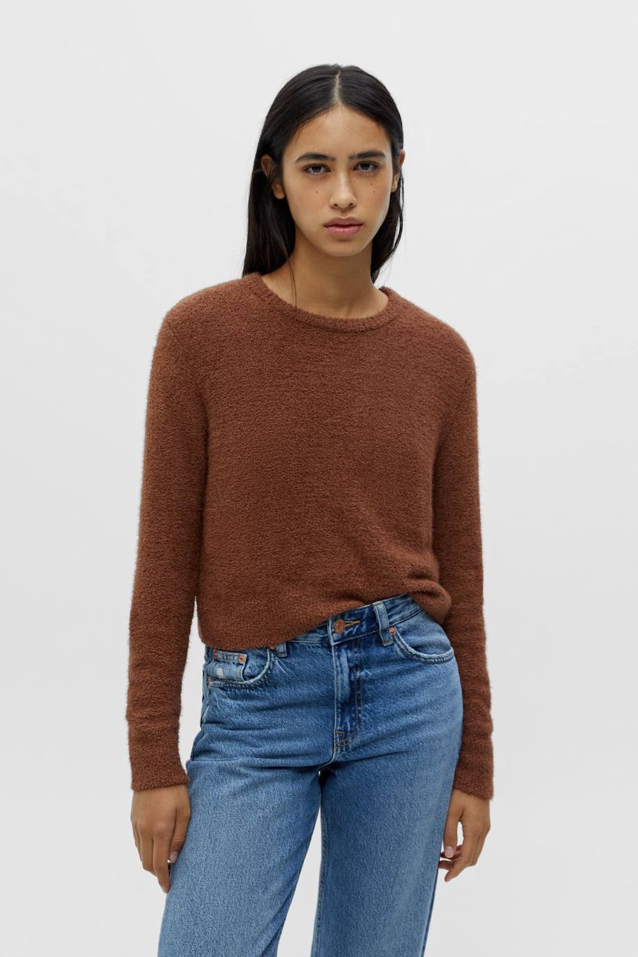 Jersey en tejido de punto efecto pelo con detalles brillantes, cuello redondo, manga larga y silueta cropped, tono dorado, de Pull&Bear. Puedes encontrarlo a 29,99 euros.