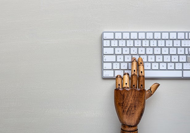 Close-Up Of Wooden Hand Figurine Typing Keyboard on a White Table