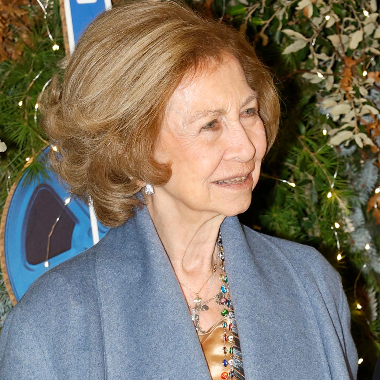 La reina Sofía con un abrigo capa en color azul.