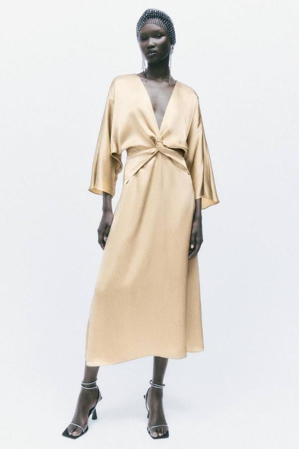 Vestido midi en tejido satinado con mangas largas anchas, escote de pico y detalle de nudo, tono dorado, de Zara. Hazte con él a 45,95 euros.