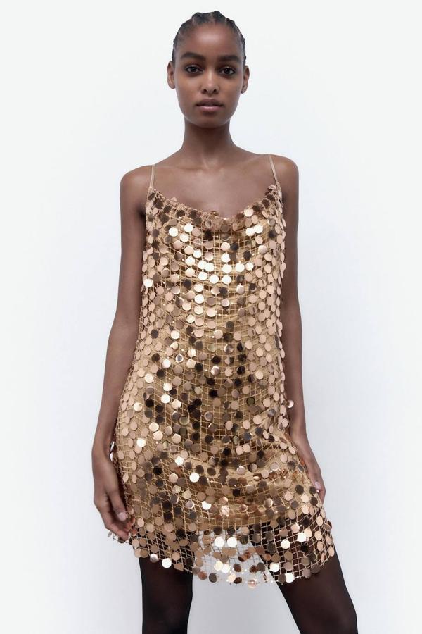 Vestido mini con escote fluido, tirantes finos y falla de lentejuelas grandes, en dorado, de Zara. Puedes comprarlo por 39,95 euros.