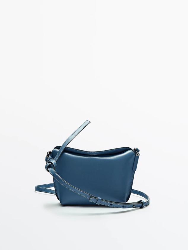 Bolso en piel con correa ajustable y forro interior en algodón. Es de color azul y tiene detalle de costuras en blanco. Precio: 69,95 euros.