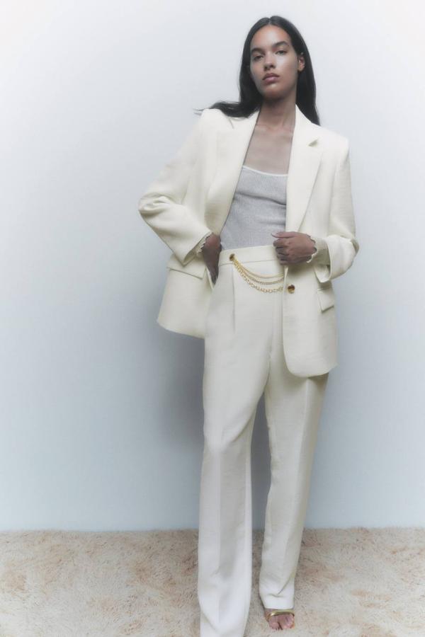 Traje con blazer recta y pantalón con detalle de cadena de dorada, en crudo, de Zara.