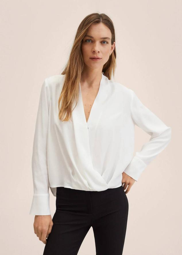 Blusa en tejido fluido con diseño cruzado, escote de pico y manga larga, color blanco. Puedes comprarla a 12,99 euros.
