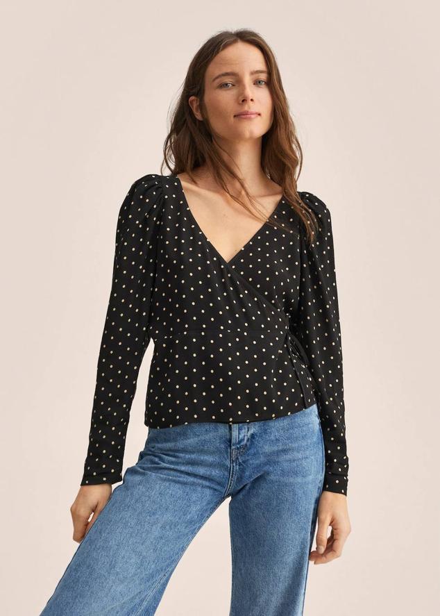 Blusa con diseño cruzado, escote de pico, manga larga abullonada y estampado de lunares blanco y negro. Te costará 6,99 euros.