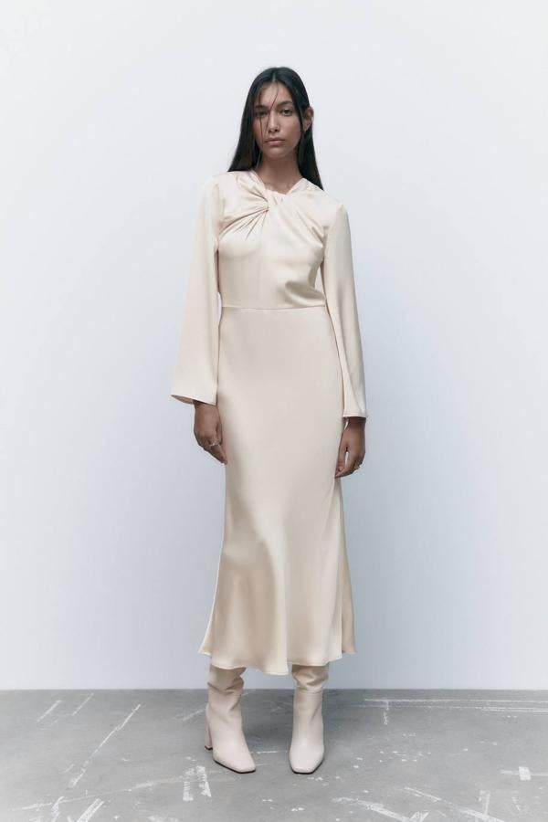 Vestido midi satinado fluido con manga larga y detalla de nudo fruncido en el cuello, en cava. Su coste rebajado es de 39,99 euros.