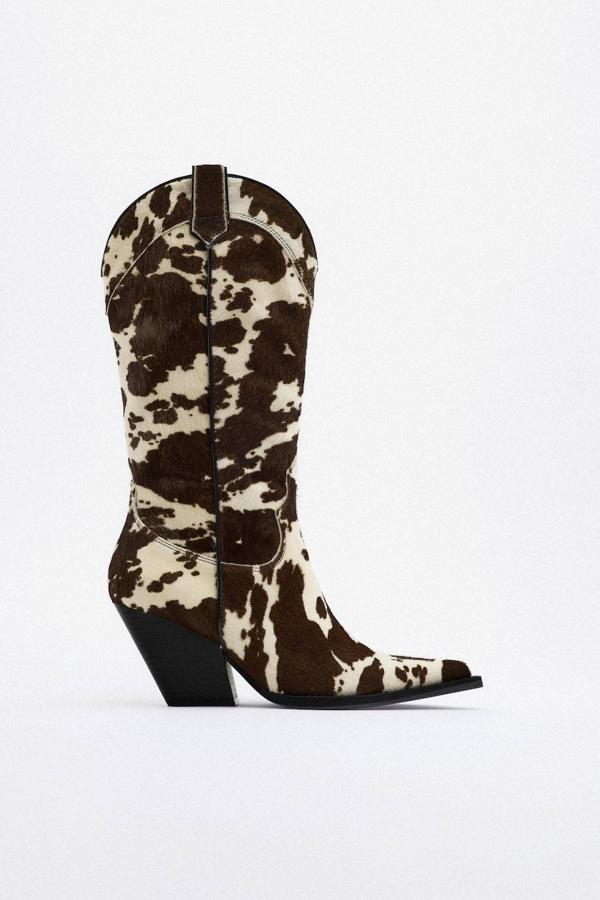 Botas cowboy en tejido de piel con tacto de pelo, terminación en punta, tacón inclinado y animal print de vaca en crudo y marrón, de Zara. Cuestan 79,99 euros, con descuento.