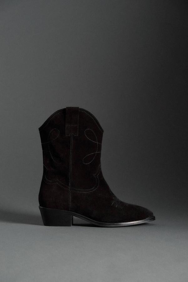 Botas cowboy en tejido de piel de serraje cos costuras decorativas, acabado en punta, tiradores y tacón bajo, color negro, de Slowlove. Puedes encontrarlas en las rebajas de Springfield por 99,99 euros.