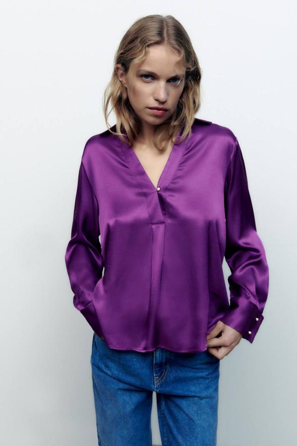 Blusa satinada con cuello solapa, escote de pico y manga larga, color morado, de Zara. Puedes comprarla de rebajas a 17,99 euros.