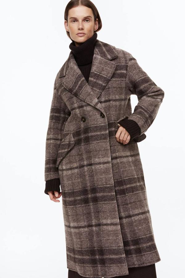 Abrigo largo en tejido de lana con diseño cruzado, cuello solapa con muesca, manga larga y estampado a cuadros marrón, de H&M. Está disponible de rebajas a 99,99 euros.