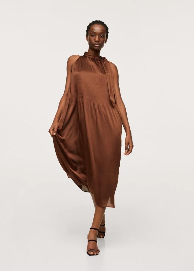 Es un vestido largo con detalles plisados en marrón chocolate. Cuenta con uno de los escotes más favorecedores, el cuello halter. Es fluido, ligero y comodísimo. Precio: 34,99 euros.