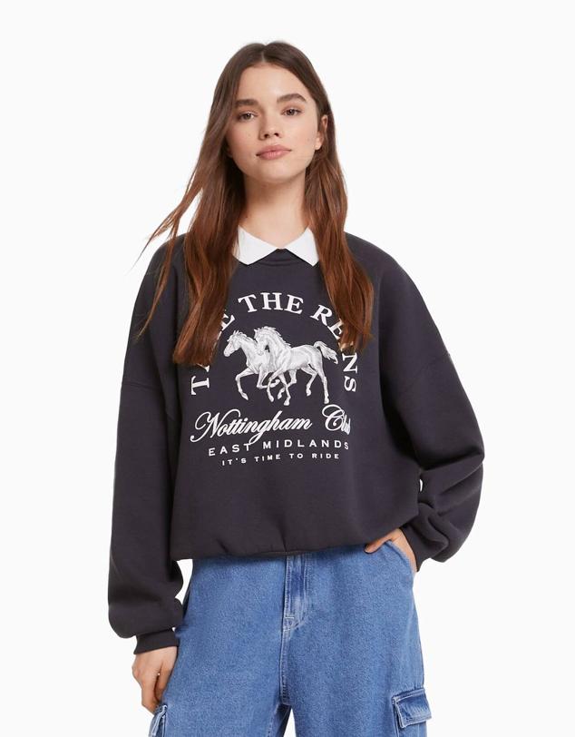 Sudadera con corte relajado, manga larga, cuello polo y detalle de bordado, azul marino, de Bershka. Su precio es de 22,99 euros.