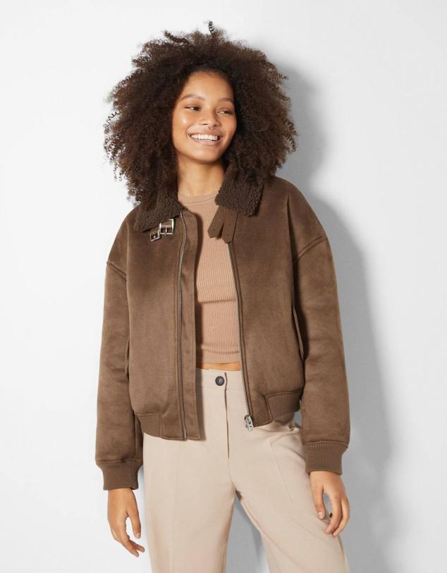 Cazadora de aviador doble faz con tejido efecto piel de ante, acabados elásticos, forro de borreguillo a tono, trabillas y bolsillos, color marrón medio, de Bershka. Podrás encontrarla por 39,99 euros.
